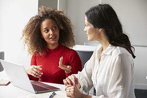 Two woman talking in front of computer
